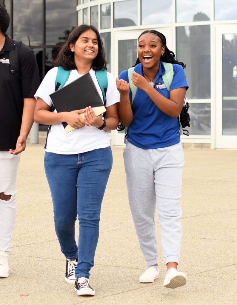 Two SUNY Niagara students walking and smiling outside on campus